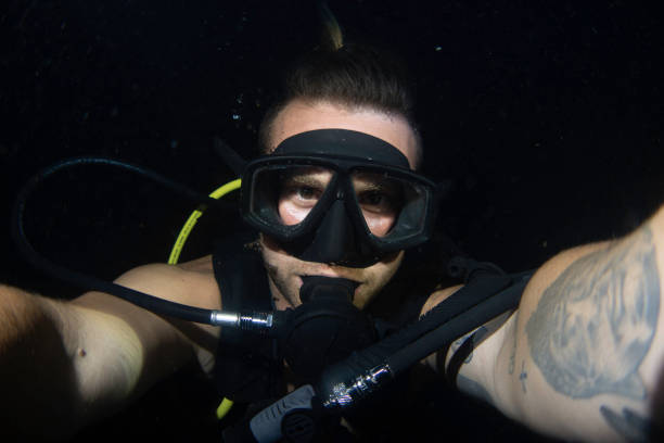 young guy doing night dive and taking a selfie stock photo