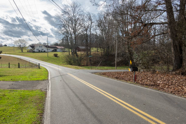 istock Rural road with farmhouse in background 1364072754