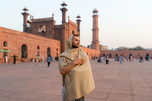 Young Caucasian man  walking near the mosque in Lahore at night