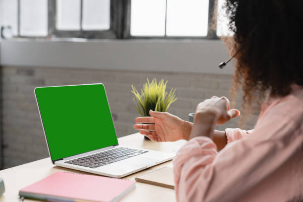 istock Customer support IT support manager. Rear view of laptop screen with copy space mockup green screen. African woman, receptionist talking online using headphones 1364074964