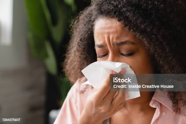 Sneezing Coughing Ill Young African Woman Using Paper Napkin Having Runny Nose Blowing Her Nose Coronavirus Infectious Disease Flu Cold Stock Photo - Download Image Now