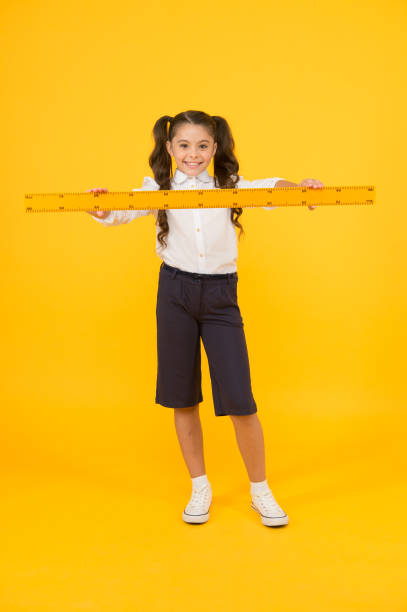 istock Studying is fun. School adorable student study geometry. Kid school uniform hold ruler. Pupil cute girl with big ruler. Geometry school subject. Education and school concept. Sizing and measuring 1364076147