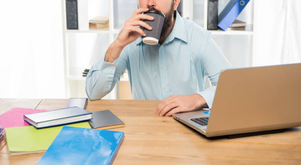 istock Professional man crop view drinking takeaway coffee sitting at office desk, coffee break 1364076327