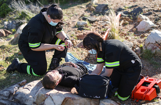 Two female paramedics assisting an injured caucasian male on a hiking trail in the Helderberg near Gordon's Bay.