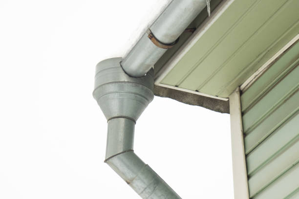 Frozen gutter in winter from the roof to the ground against the background of the green wall of the house Frozen gutter in winter from the roof to the ground against the background of the green wall of the house. Cold weather steel gutters stock pictures, royalty-free photos & images