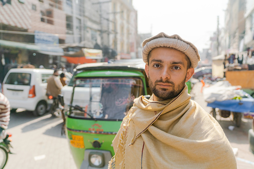 Man in traditional clothes  standing on crowded street of Lahore, Pakistan