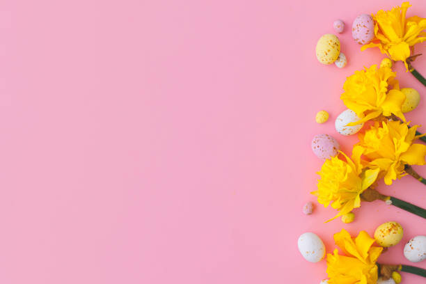 istock Happy Easter! Colorful Easter chocolate eggs and daffodils flowers border on pink background. Stylish Easter flat lay. Greeting card or banner template 1364089924