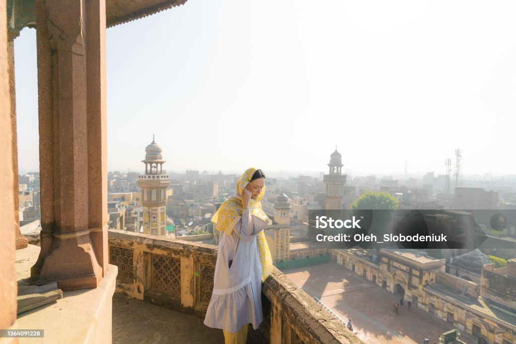 Woman in hijab standing near the minaret and looking at Lahore city from above Young Caucasian female tourist in hijab standing near the minaret and looking at Lahore city from above Women Stock Photo