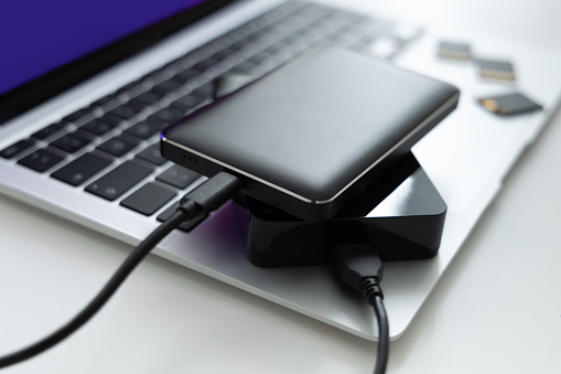 External hard drives with USB connection are on a modern laptop. memory cards can be seen in the background. Concept for safe handling of data, data backup, installation
