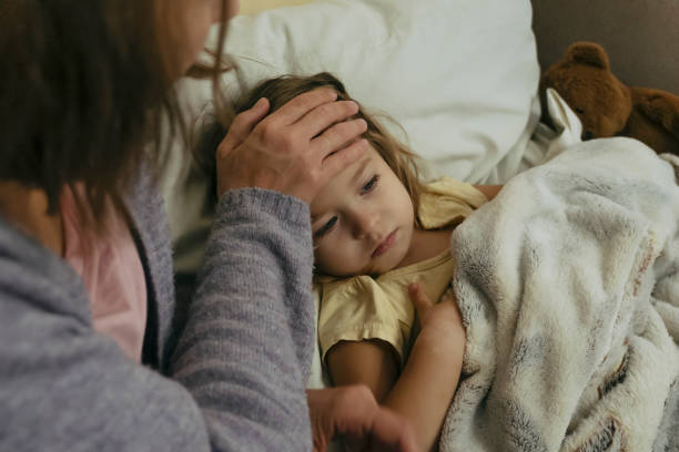 porträt eines traurigen, vertieften kranken mädchens und ihrer mutter, die die stirn ihrer tochter berührt. - family child portrait little girls stock-fotos und bilder