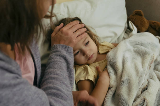 portrait d’une petite fille malade triste et absorbée et de sa mère touchant le front de sa fille. - illness photos et images de collection