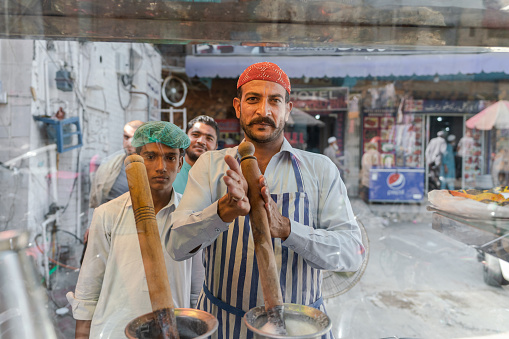 Lahore, Pakistan  - October 31, 2021:  Two men  making drinks on street food market in Lahore, Pakistan