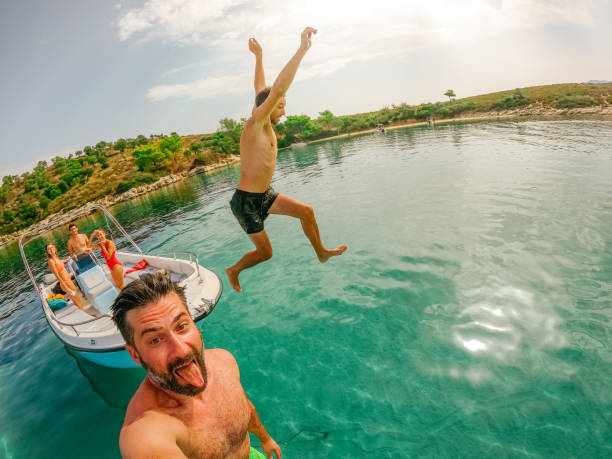 Our summer vacation Photo of several friends having fun while jumping off the motorboat and bathing in the sea. yacht selfie stock pictures, royalty-free photos & images