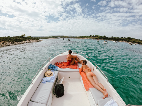 Photo of two friends sunbathing and enjoying on the yacht.