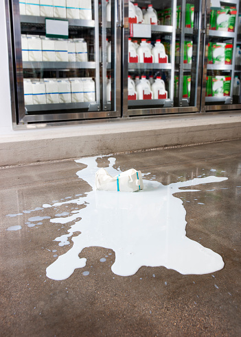 A carton of milk spilled on the floor of a supermarket.  A loss prevention and occupational health and safety topic. Slips trips, and falls are a major cause of injuries.