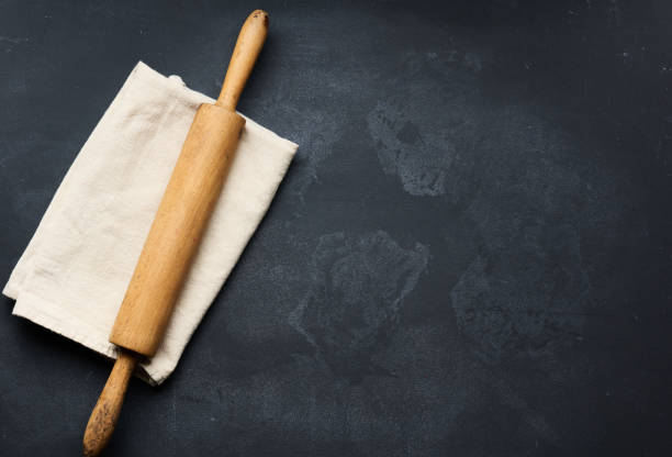 old wooden rolling pin for rolling dough on a black background, top view. Copy space