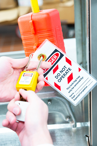 Safety lock out with a tag on a piece of equipment that is shut off for safety reasons.  A lock out physically locks the system in a safe mode. An occupational health and safety topic.