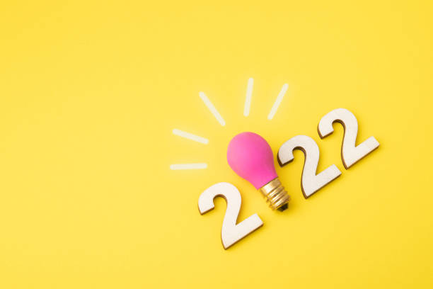 números 2022 com lâmpada em fundo amarelo como ideia de símbolo criativo - alternative energy data fuel and power generation light bulb - fotografias e filmes do acervo