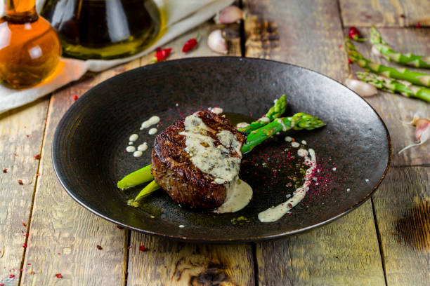 istock roast beef Steak with asparagus on black plate on wooden table 1364104142