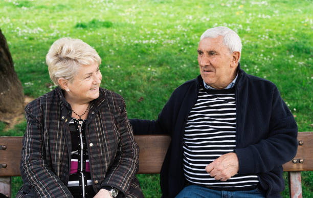 istock Senior couple chatting while sitting on park bench 1364105203