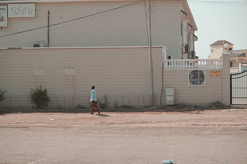 Djibouti, Djibouti - May 21, 2021: A Djiboutian man in local dress walking on the road. Editorial shot in Djibouti