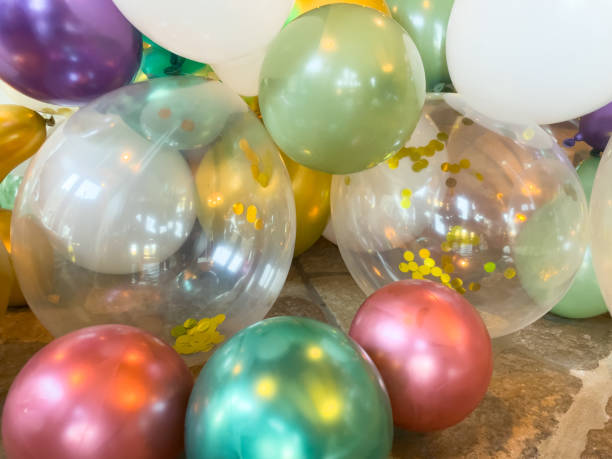 Close up of latex shiny balloons for party celebration – clear balloon with gold confetti inside stock photo