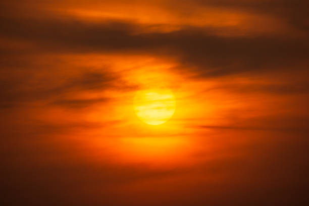 Orange sky and sun shining behind clouds nature dramatic background