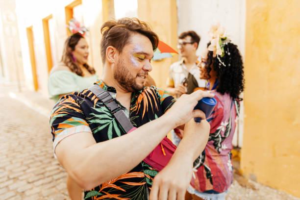 cuidado durante o carnaval. homem usando protetor solar durante bloco de carnaval - applying make up - fotografias e filmes do acervo