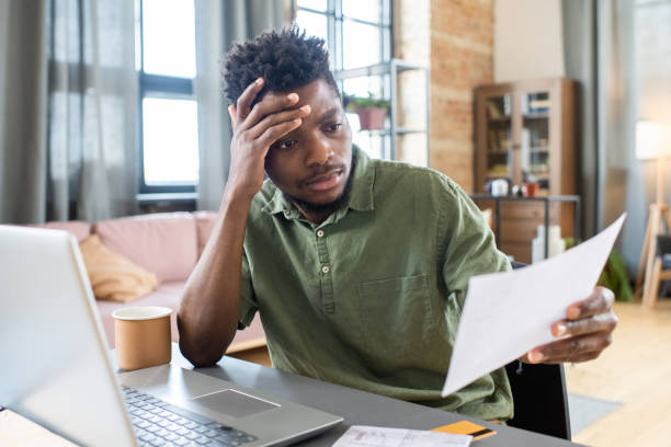 istock Young stressed African businessman looking through unpaid bill 1364117439