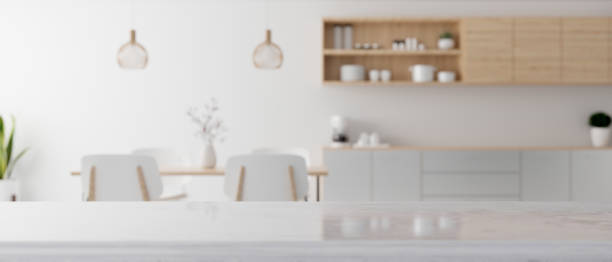 Modern white kitchen countertop with a copy space over blurred modern minimal dining room
