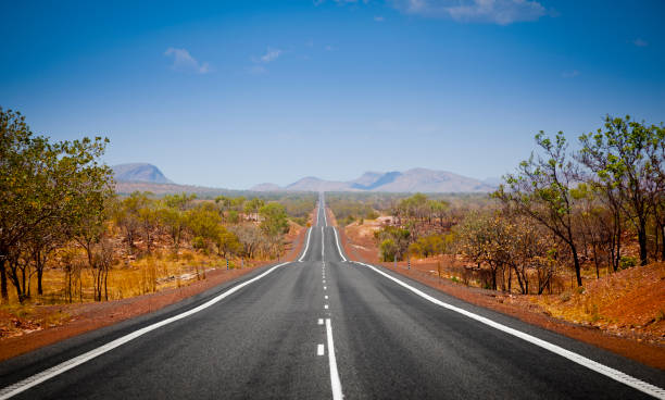 Open Road The open road in Kimberly, Western Australia. Straight single lane asphalt road stretching into the distance with mountains in the background. Holiday adventure. australian bush stock pictures, royalty-free photos & images