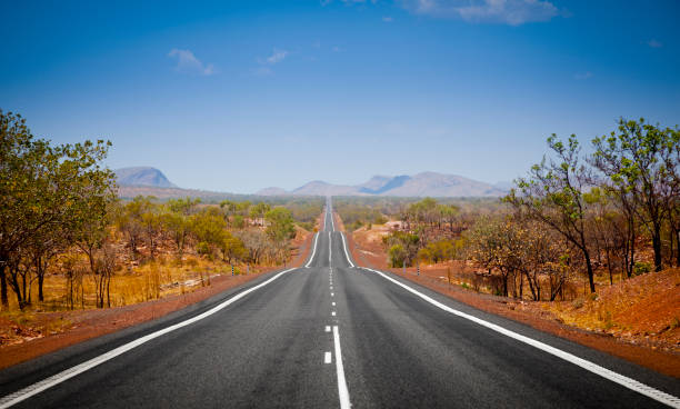 Open Road The open road in Kimberly, Western Australia. Straight single lane asphalt road stretching into the distance with mountains in the background. Holiday adventure. outback stock pictures, royalty-free photos & images