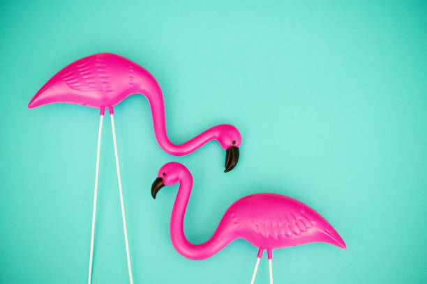 couple de flamants roses en plastique brillant sur un fond sarcelle vibrant avec espace de copie - plastic flamingo photos et images de collection