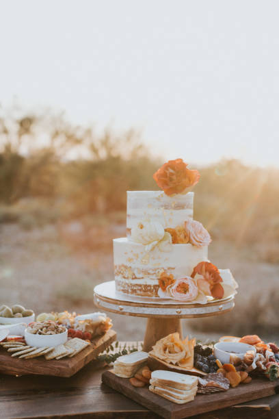 Floral Wedding cake White cream wedding cake with red and pink flowers and food charcuterie near it. eloping stock pictures, royalty-free photos & images