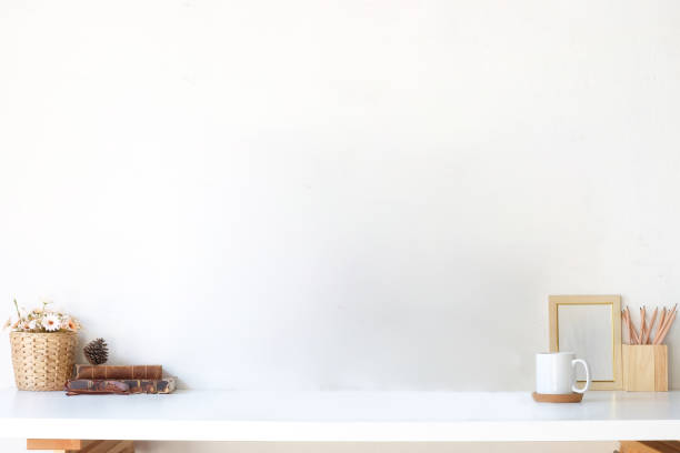 istock Minimal workspace with picture frame, book, coffee cup and pencil holder on white table. Copy space for your advertising text. 1364130146