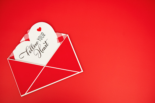 Valentine's Day background with envelope and message on a vibrant red background with copy space