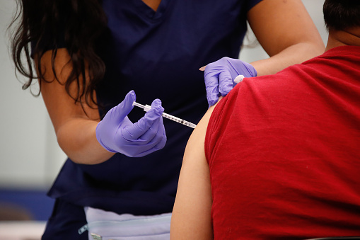 A patient receives a dose of the Covid-19 vaccine through intramuscular injection by a registered nurse.