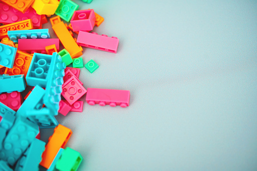 Colorful plastic toy bricks on a pale blue background with space for copy