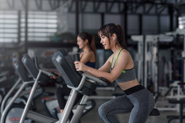 giovane donna asiatica che si allena sulla cyclette in palestra. - spinning instructor exercising gym foto e immagini stock