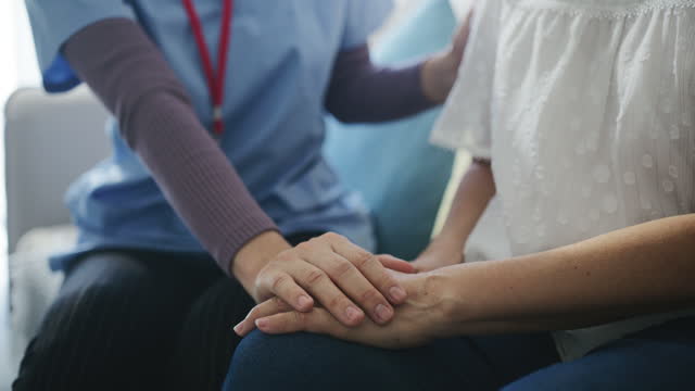 Caregiver talking to senior woman and holding hands