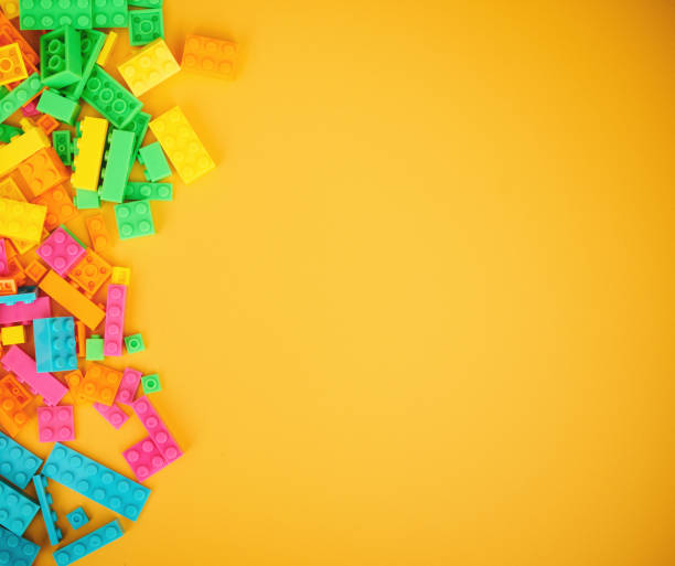 istock Collection of scattered plastic toy bricks on a bright yellow background with copy space 1364135424