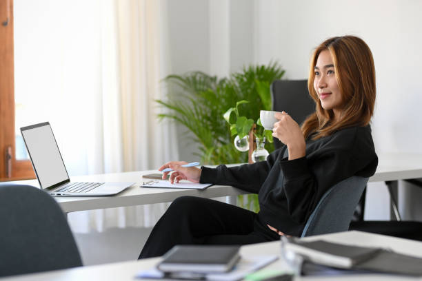 istock Businesswoman sipping coffee while working on her laptop computer. 1364135464
