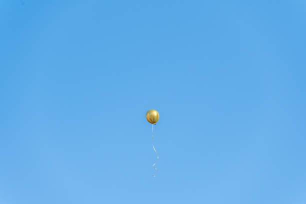 istock A golden balloon flew under the blue sky and white clouds 1364138090