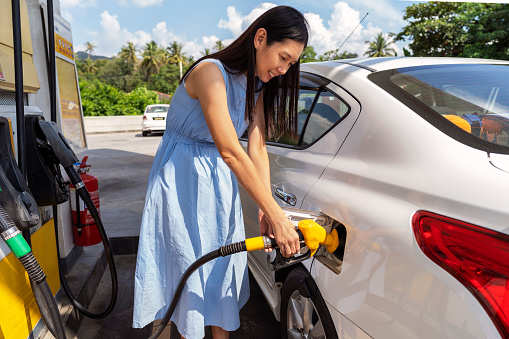 Female customer at self service petrol station refueling her car - Business concepts