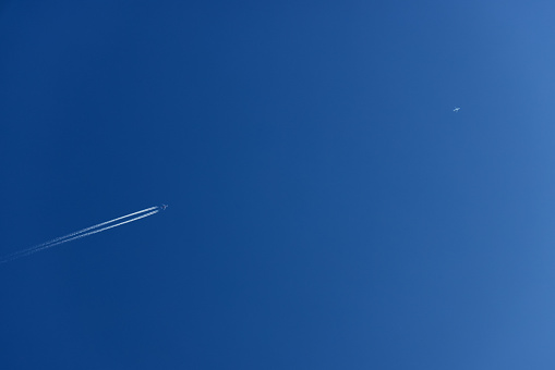 Contrail from airplane on blue sky, white cloud trail