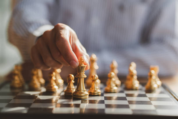istock businessman hand moving gold Chess King figure and Checkmate opponent during chessboard competition. Strategy, Success, management, business planning, disruption and leadership concept 1364148588