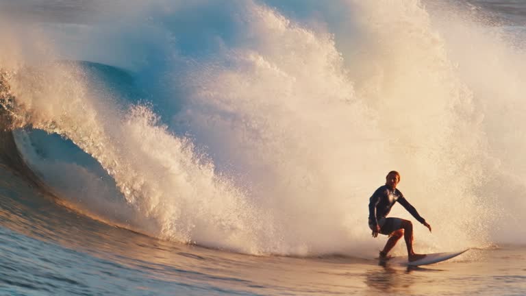 Surfer rides the powerful ocean wave at sunset