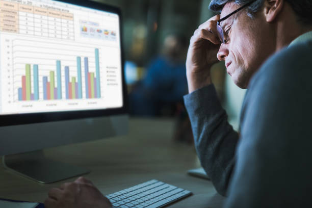 istock Overworked businessman analyzing charts on a computer in the office. 1364150707