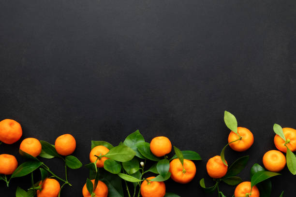 istock Mandarins or clementines with leaves on a black background. Top view. 1364154877