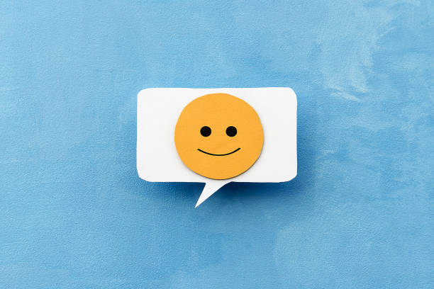 istock Yellow slightly smiling smiley face on the callout for text on a blue background. The concept of mood selection and customer feedback. 1364155142